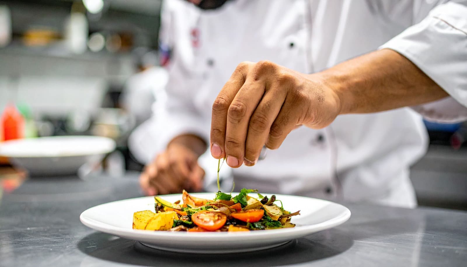 Un cocinero emplatando un plato en la cocina de un restaurante