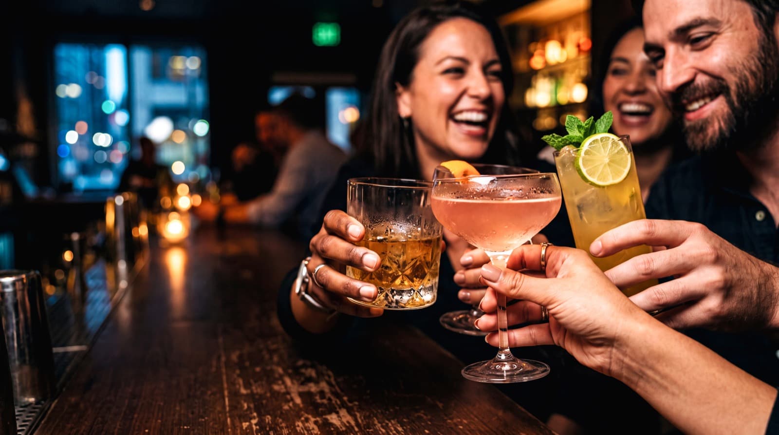 Tres personas brindando con cócteles en un bar